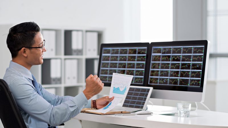 Happy excited financial broker looking at the business chart in his hand