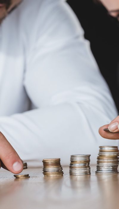 cropped image of business advisers stacking coins on table in office