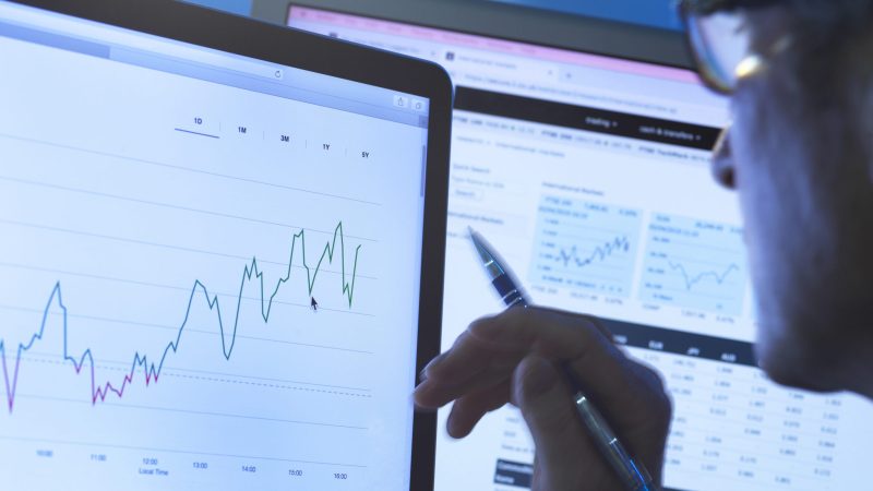 Financial services, stock analyst researching share price data of a company on the computer