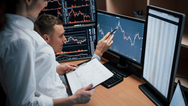Business don't do itself, you need to struggle to achieve good results Team of stockbrokers are having a conversation in a office with multiple display screens.