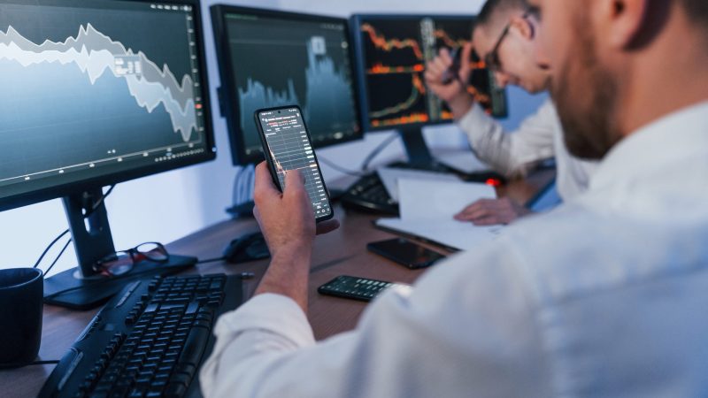 Using the phone. Two stock traders working in the office with exchange technology.